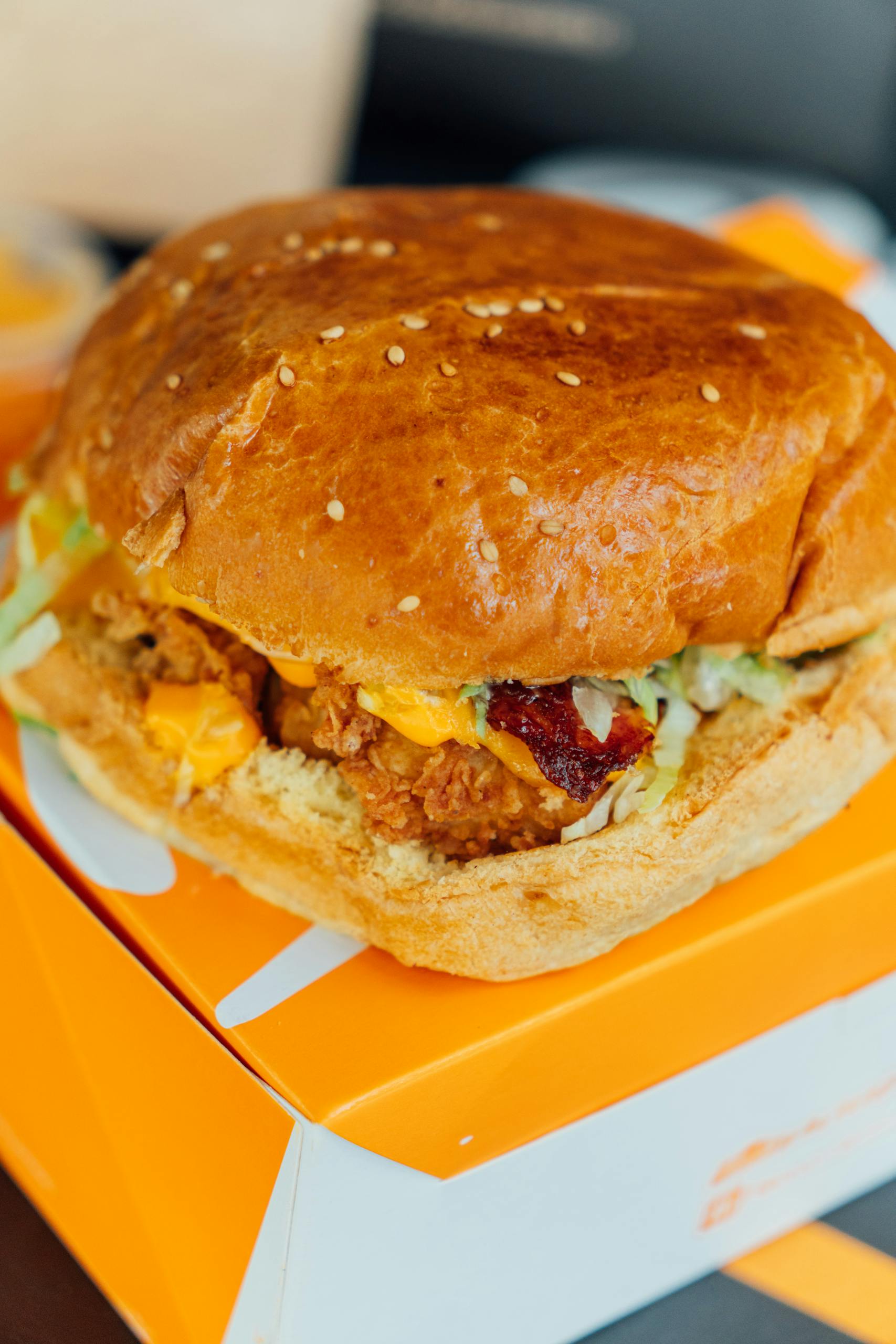 Close-up of a crispy chicken sandwich with lettuce and cheese in a box.