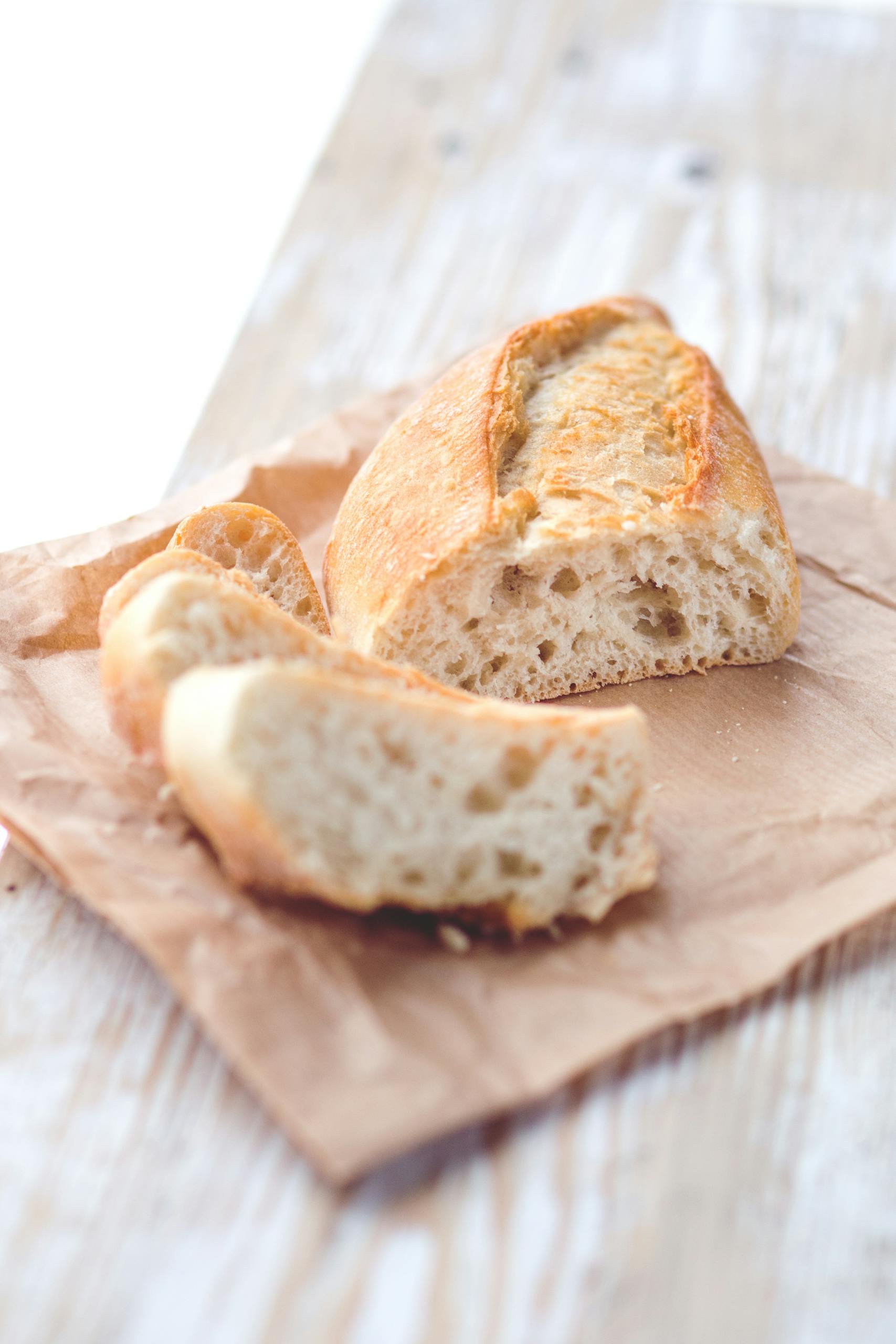 Close-up of a sliced baguette on parchment paper, showcasing its crusty texture.