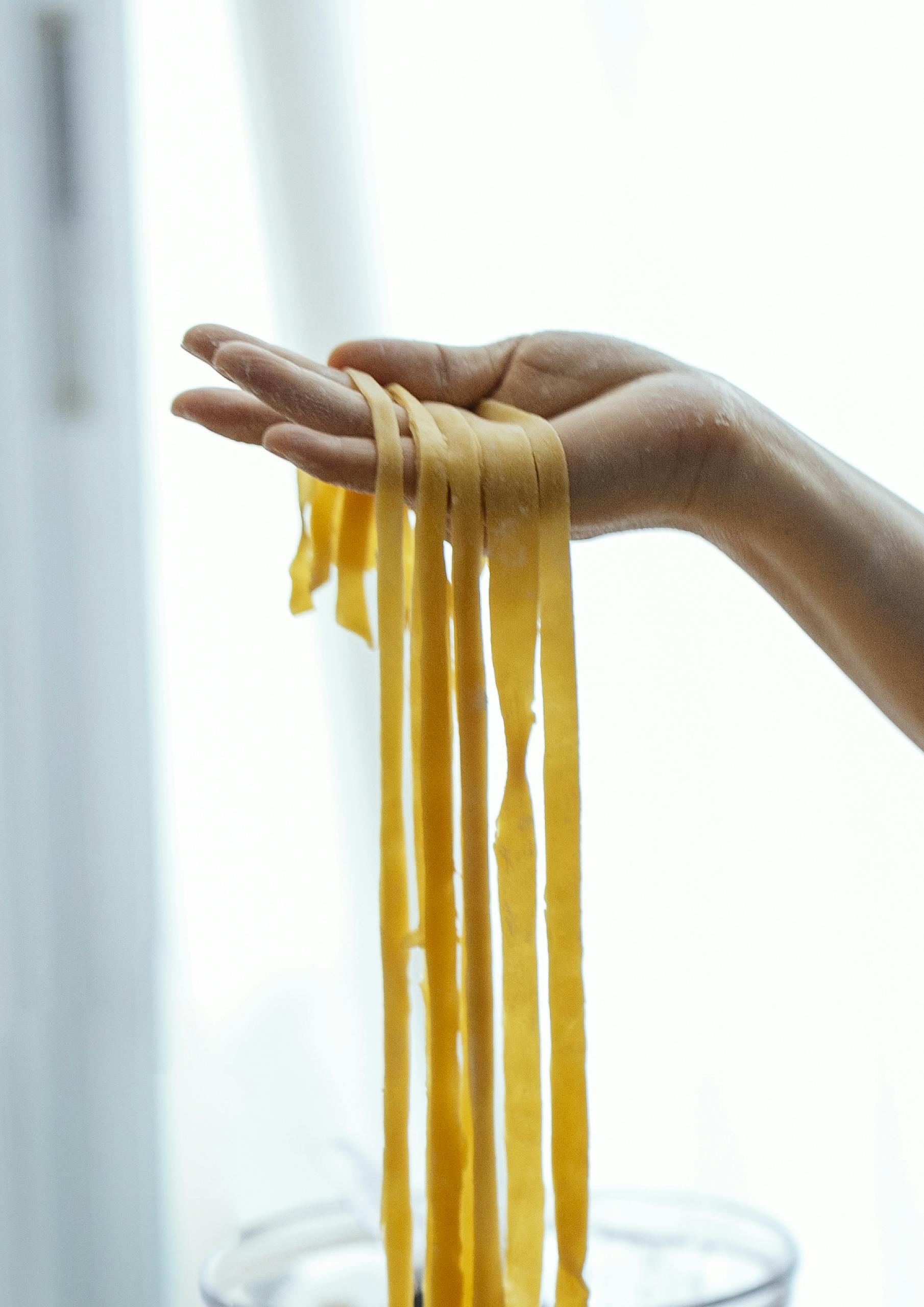 Close-up of handmade fresh pasta being prepared in a kitchen setting.