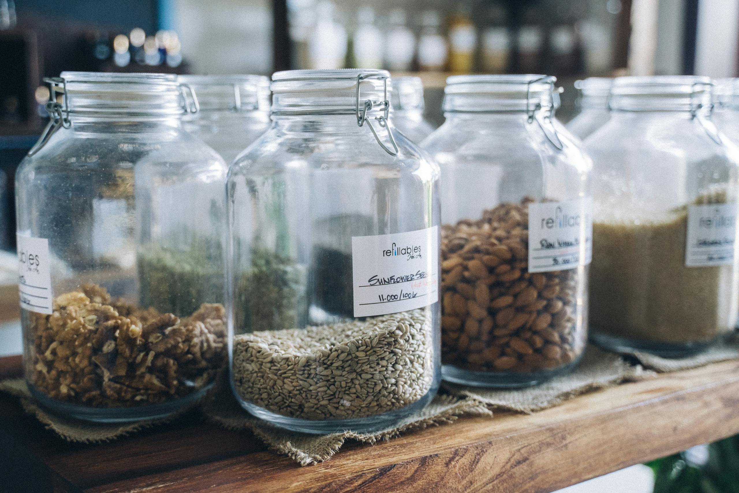 Glass jars filled with organic seeds and nuts on display in an eco-friendly store.