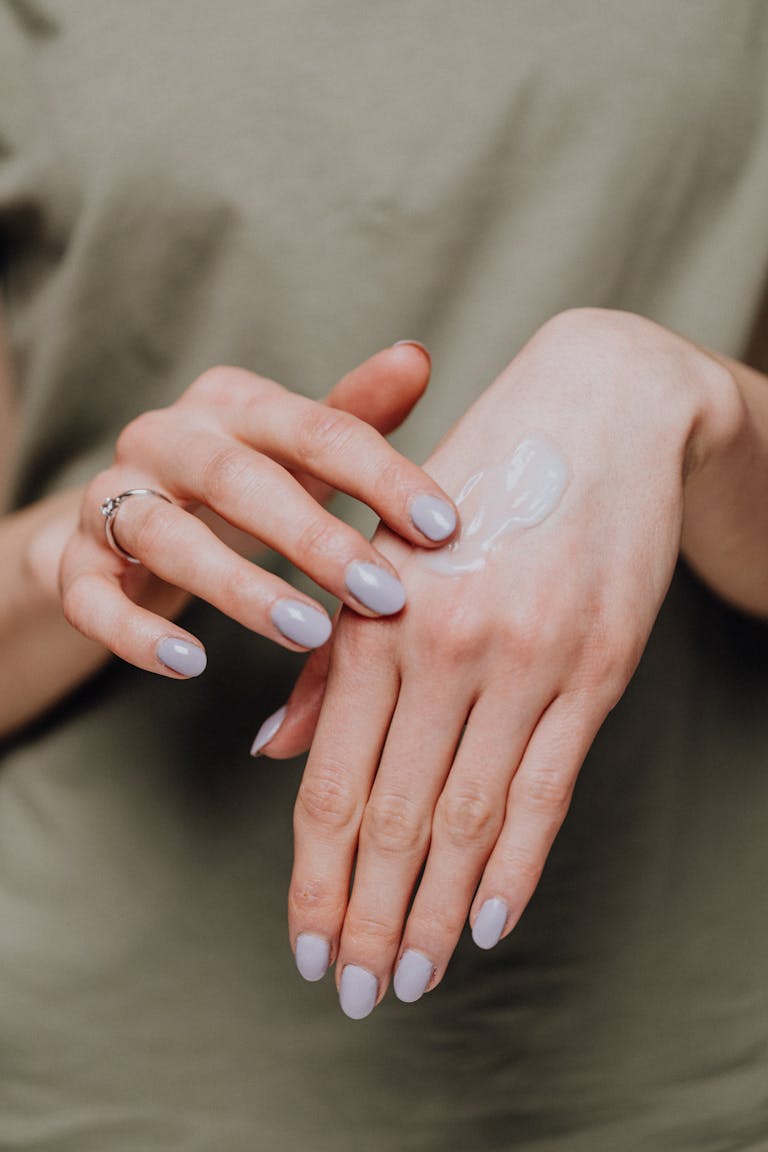 Close-up of female hands applying moisturizer cream for smooth skin care.