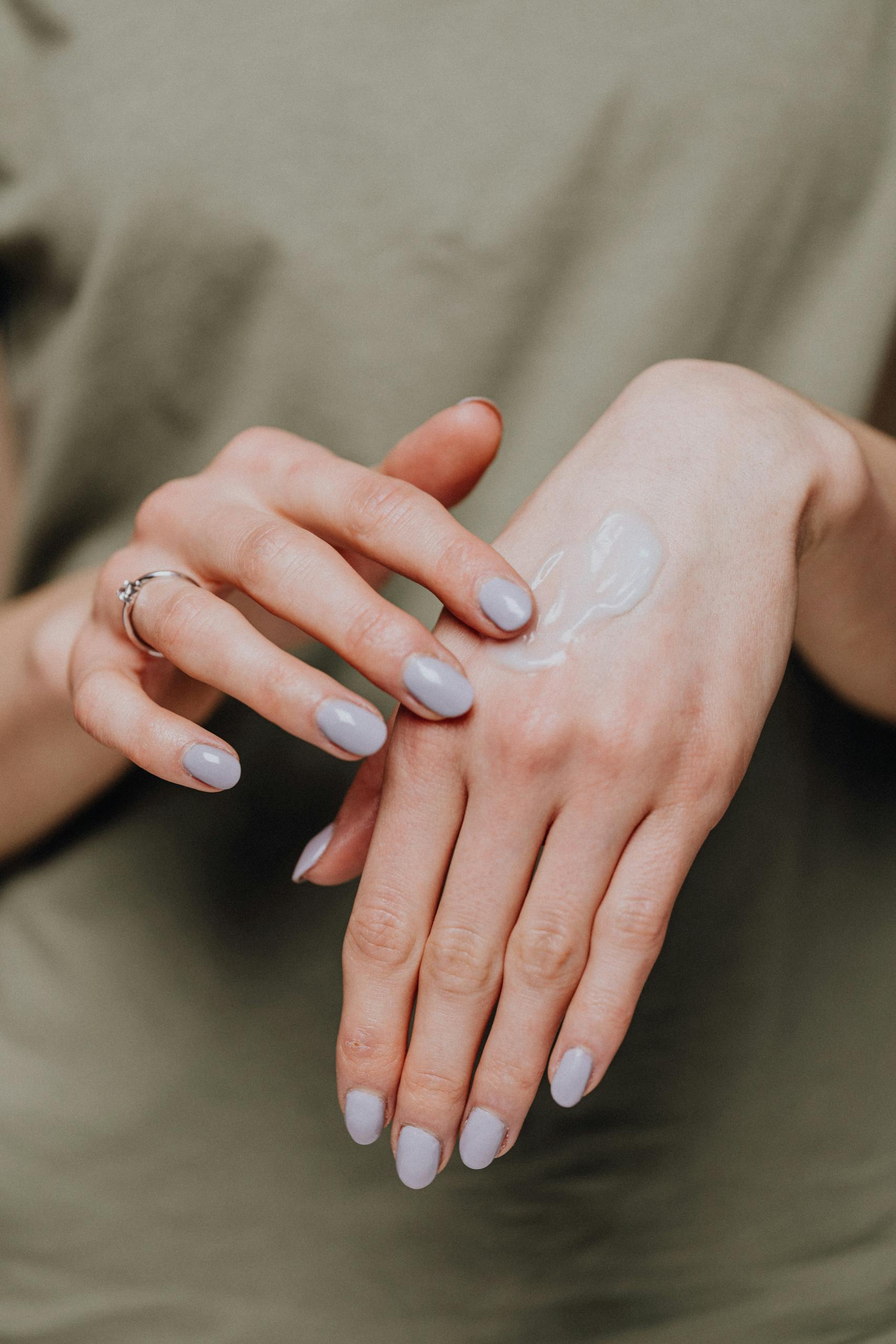 Close-up of female hands applying moisturizer cream for smooth skin care.
