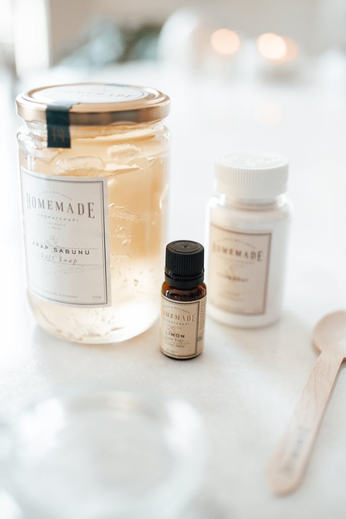 Close-up of homemade natural skincare products in glass jar and vial on white background.