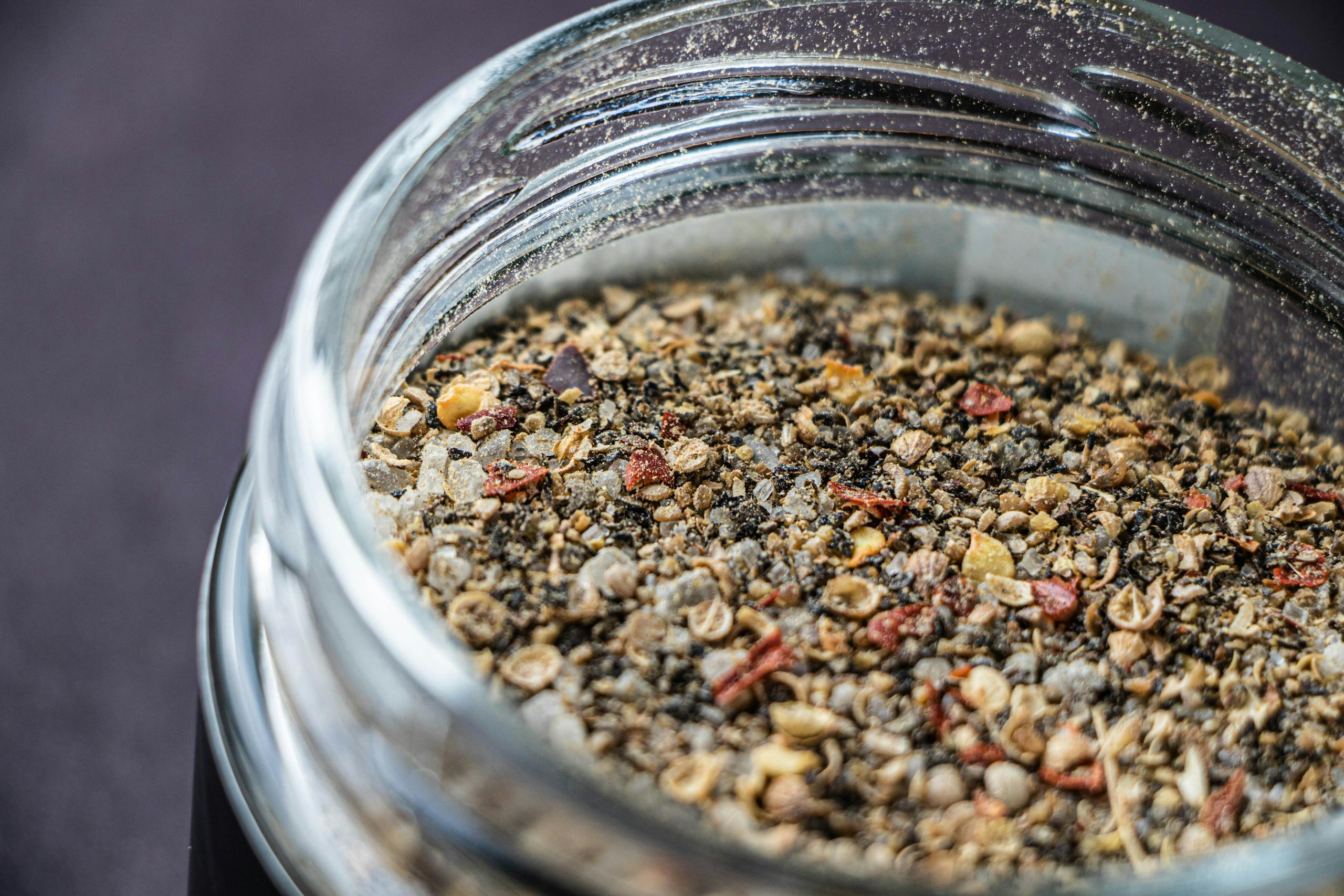 Detailed macro shot of a spice jar filled with assorted ground seasonings and seeds.
